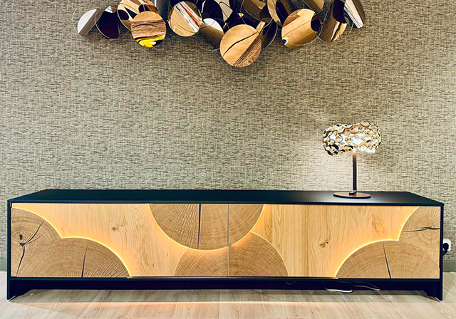 Buffet en bois naturel avec motifs circulaires et éclairage LED intégré, lampe sculpturale et décoration murale artistique.