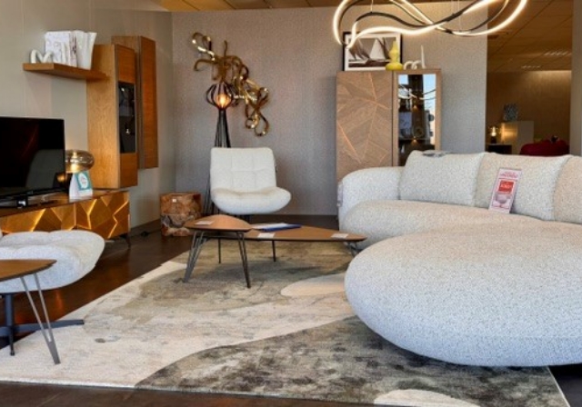 Salon design exposé chez Mobilier de France Saint-Lô, avec canapé blanc contemporain, fauteuil assorti, meuble TV en bois sculpté et tapis abstrait sur sol foncé